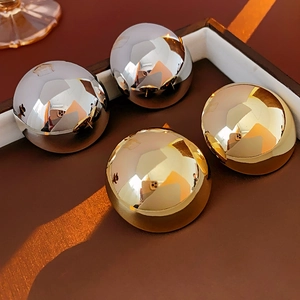Detailed view of glossy gold and silver spherical stud earrings with a mirrored surface
