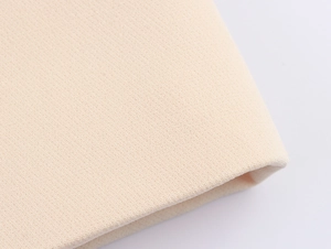 Detailed macro view of soft beige knitted fabric texture showing its weave and thickness