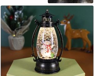 Macro shot of bronze snowman lantern with glitter snow and interior festive lighting