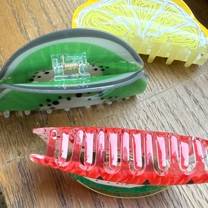 Close-up of lemon, watermelon, and kiwi acrylic fruit hair claws on wooden table