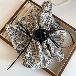 Detail of bohemian paisley print fabric bow hair claw clip displayed in a wooden jewelry box