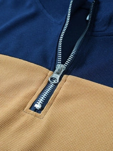 Détail du tricot gaufré bleu marine et camel avec une fermeture éclair en métal haut de gamme