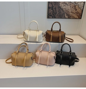 Close-up of pleated synthetic leather texture and golden metal hardware on the bucket bag