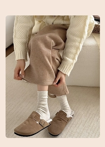 Detail of brown suede clog with metal buckle and warm wool lining in a cozy home setting