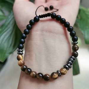 Close-up of Morse code bracelet with tiger eye beads and matte black stones on wrist