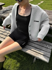 Cardigan da donna in maglia grigia con bottoni e pantaloncini sportivi neri all'aperto
