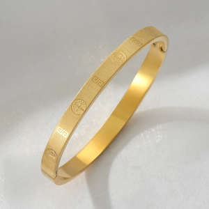 Gold stainless steel bangle with religious relief patterns and matte geometric finish