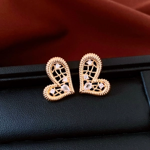 Gros plan de boucles d'oreilles cœur dorées avec texture maillée et accents de zircon