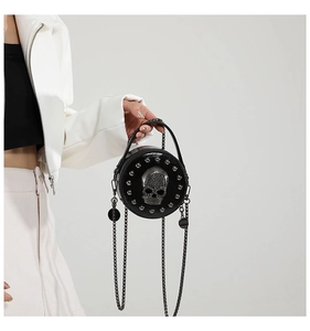 Macro shot of black leather round crossbody bag featuring silver skull and stud details