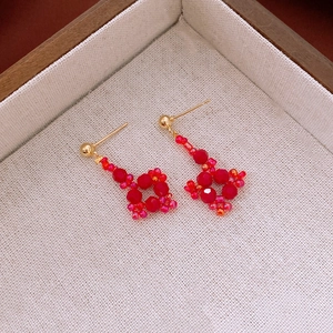 Vue macro de boucles d'oreilles géométriques perlées rouges avec clous dorés