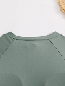 Détail des coutures raglan et de la texture en maille vert sauge du maillot de bain
