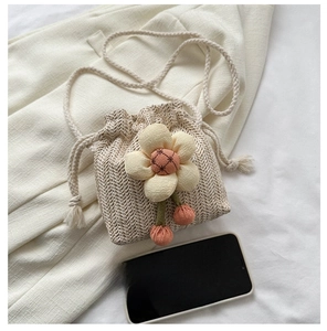 Dettaglio della mini borsa a secchiello in paglia crema con fiore in tessuto e coulisse
