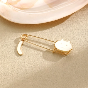 Detail of cute cat enamel safety pin with hanging tail on soft textured background