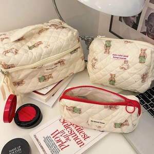 Quilted cotton vanity bags with forest bear patterns in various sizes on a desk