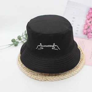 Classic black cotton bucket hat with white 'something' embroidery on a decorative mat