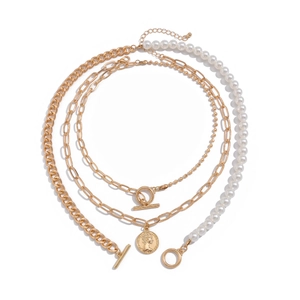 Close-up of layered gold necklace with baroque pearls and a vintage coin pendant