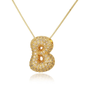 Macro detail of golden bubble letter B pendant necklace with pavé zircon settings