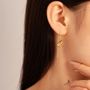 Gros plan de boucles d'oreilles pétales dorées sur modèle montrant le métal poli