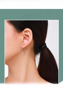 Detail shot of minimalist S925 sterling silver curved line earrings worn on an ear