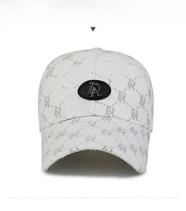 Detailed view of white baseball cap with letter pattern and silver metal logo plate