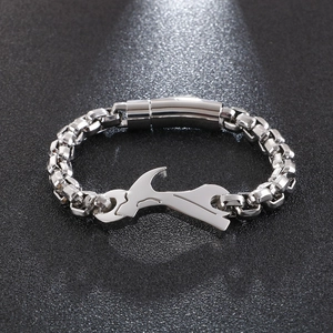 Detail shot of silver hip hop bracelet featuring wrench and hammer tool link on black surface