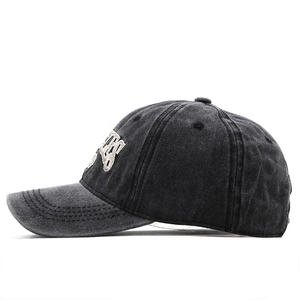 Detailed side view of washed black cotton baseball cap with white letter embroidery