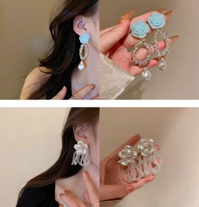 Detail of blue rose and pearl earrings alongside white flower crystal tassel earrings