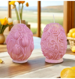 Dettaglio di due candele rosa a forma di uovo con motivi a rilievo di tulipani e rose