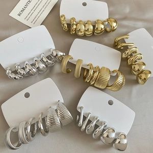 Detailed close-up of mixed gold and silver hoop earring set on an elegant fabric background