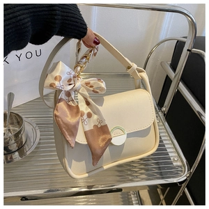 Detail of off-white leather crossbody bag featuring a silk scarf handle and metal clasp