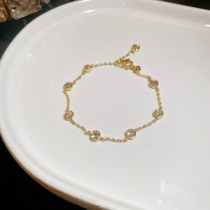 Detail of gold chain bracelet with bezel-set stones on white ceramic plate