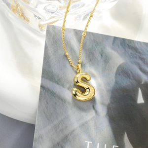 Dettaglio collana con ciondolo lettera S in oro 18K con catena a perle decorativa