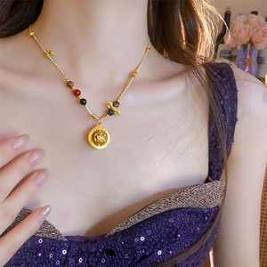 Detail view of woven gold-plated necklace with hollow pendant and colorful beads on a model