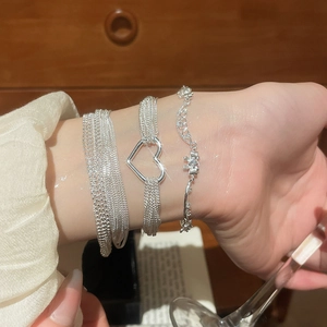 Silver multi-layer beaded bracelet with zircon heart charm and floral detail on wrist