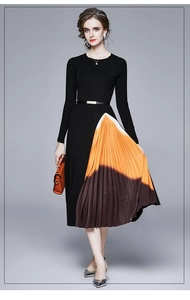 Détail d'une robe plissée en maille avec boucle dorée et dégradé orange sur l'ourlet