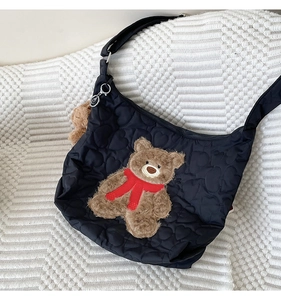 Detail of black quilted heart nylon bag featuring a 3D brown plush teddy bear charm