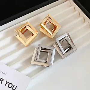 Polished geometric interlocking rhombus earrings in gold and silver finish on display