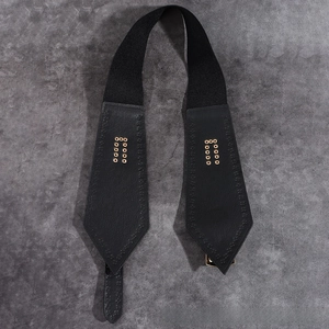 Close-up of black elastic waist belt featuring arrow leather ends and gold metal eyelets