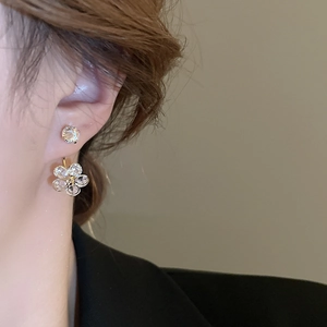 Close-up of elegant gold flower petal earrings with sparkling cubic zirconia on a model