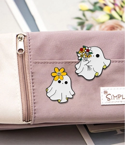 Close-up of cute white ghost enamel pins with rhinestones on a canvas backpack
