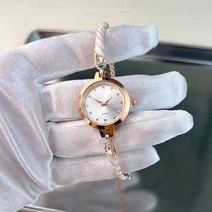 Detail of rose gold quartz watch featuring white enamel bracelet and rhinestone indices