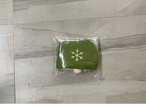 Detail of Christmas gnome wine bottle cover in green knit with white snowflake patterns