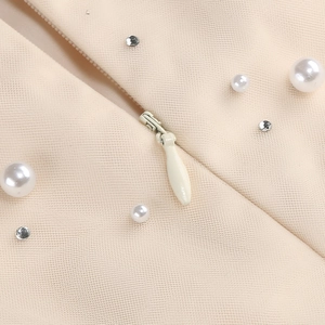 Detailed view of apricot mesh dress with faux pearls, rhinestones, and invisible zipper