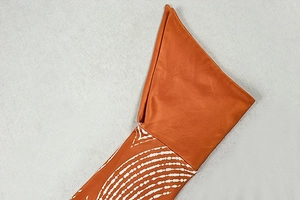 Detailed close-up of orange sleeve cuff with white wave patterns on a smooth fabric