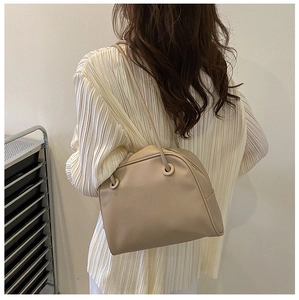 Detail of minimalist beige PU leather shoulder bag with circular strap attachment and matte finish