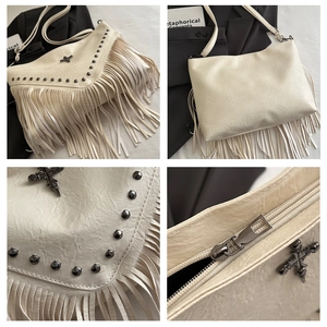 Detail of white gothic crossbody bag with metallic cross charm, rivets and long fringe