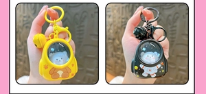 Close-up of yellow and black astronaut bear keychains with matching bells and clips