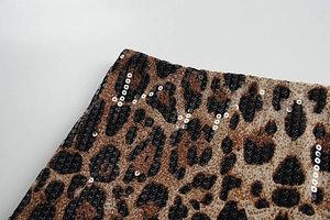 Dettaglio del tessuto leopardato con paillettes scintillanti e trama marrone