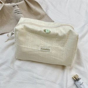 Detail of cream rose cosmetic bag with 3D striped lace texture and floral accent