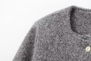 Close-up of dark grey wool bouclé jacket featuring a premium textured fabric and gold button